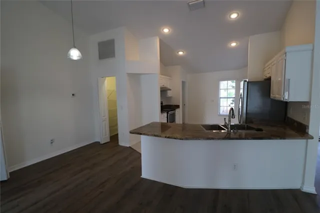 a kitchen with kitchen island granite countertop a sink a counter top space and cabinets