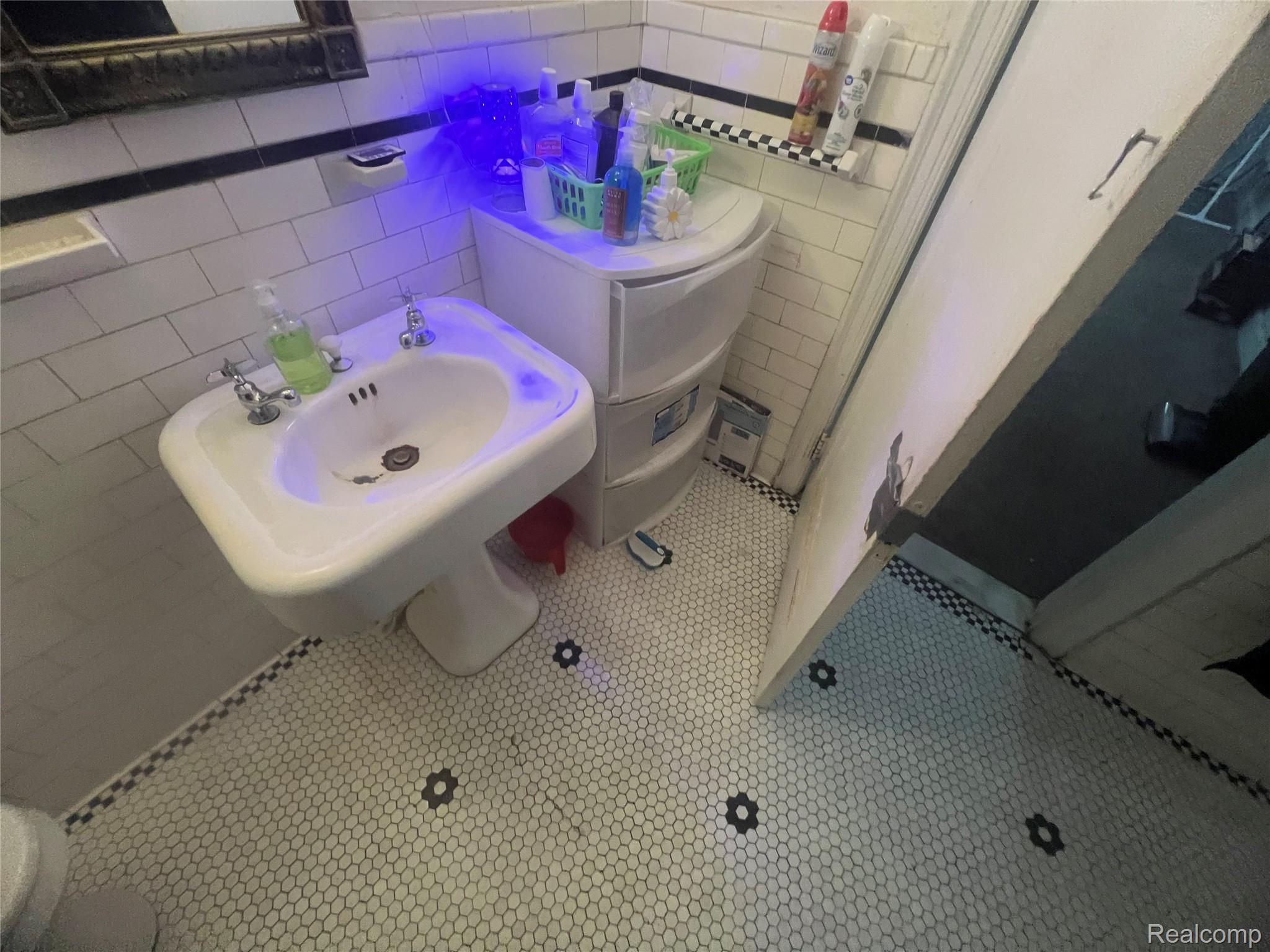 17311 Santa Rosa Drive Detroit, MI 48221 - Photo 85 of 89 Bathroom featuring a pedestal sink, white subway tile walls, and hexagon mosaic tile flooring with accent details