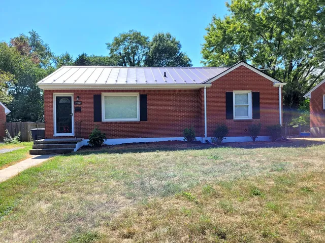 a view of a house with a yard and large tree