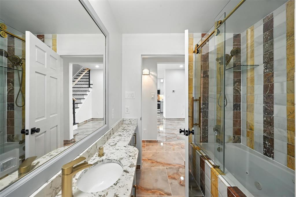 934 Elwood Road Irving, TX 75061 - Photo 31 of 40 a bathroom with a granite countertop double vanity sink a mirror a bathtub and shower