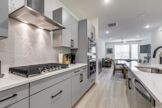 a kitchen with stove a sink dishwasher and white cabinets with wooden floor