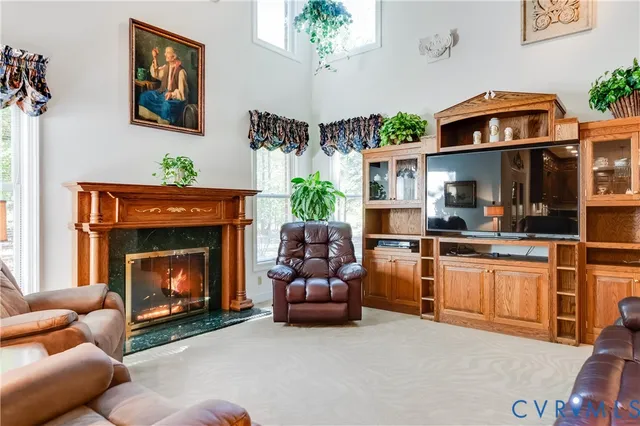 a living room with stainless steel appliances furniture a fireplace and a chandelier