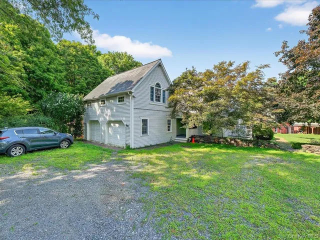 a view of a house with a big yard and large trees