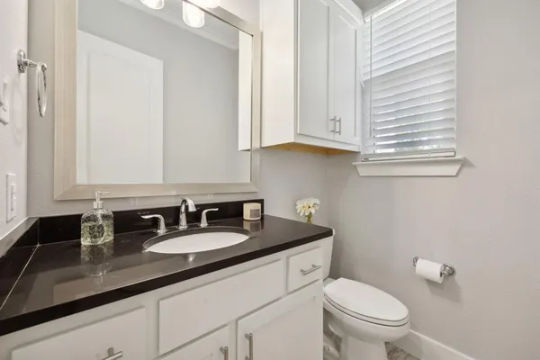 a bathroom with a granite countertop sink a toilet and a mirror
