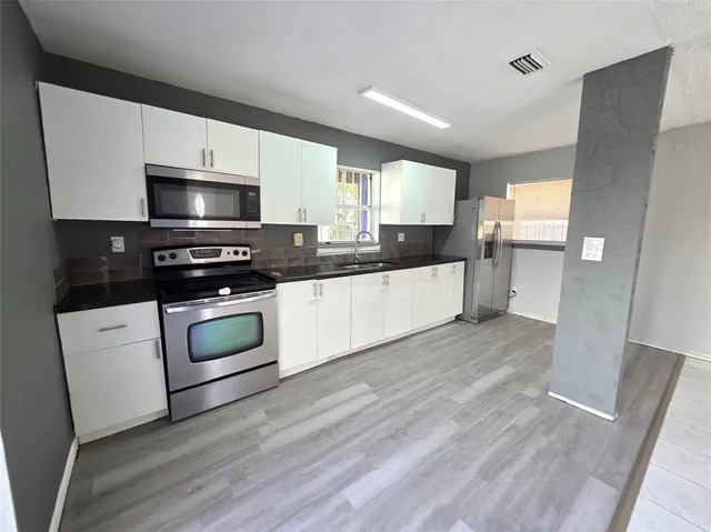 a kitchen with stainless steel appliances a stove a sink and white cabinets
