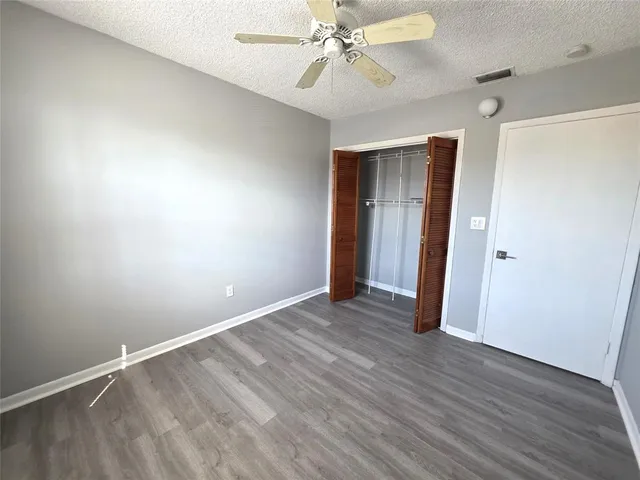an empty room with wooden floor and fan