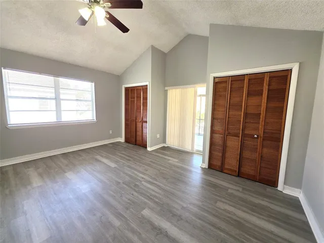 an empty room with wooden floor cabinet and windows