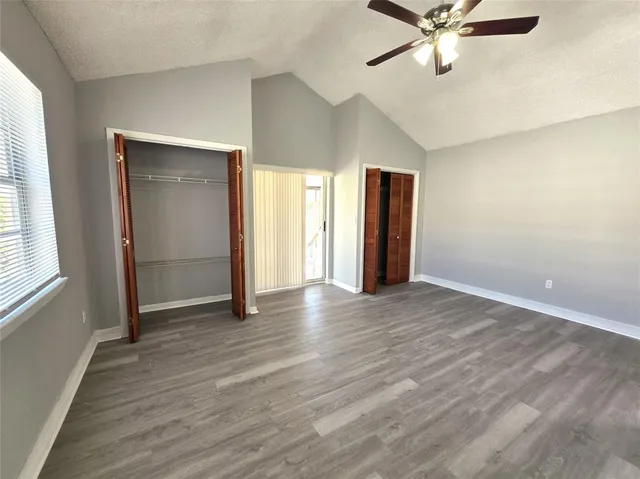 an empty room with wooden floor closet and windows