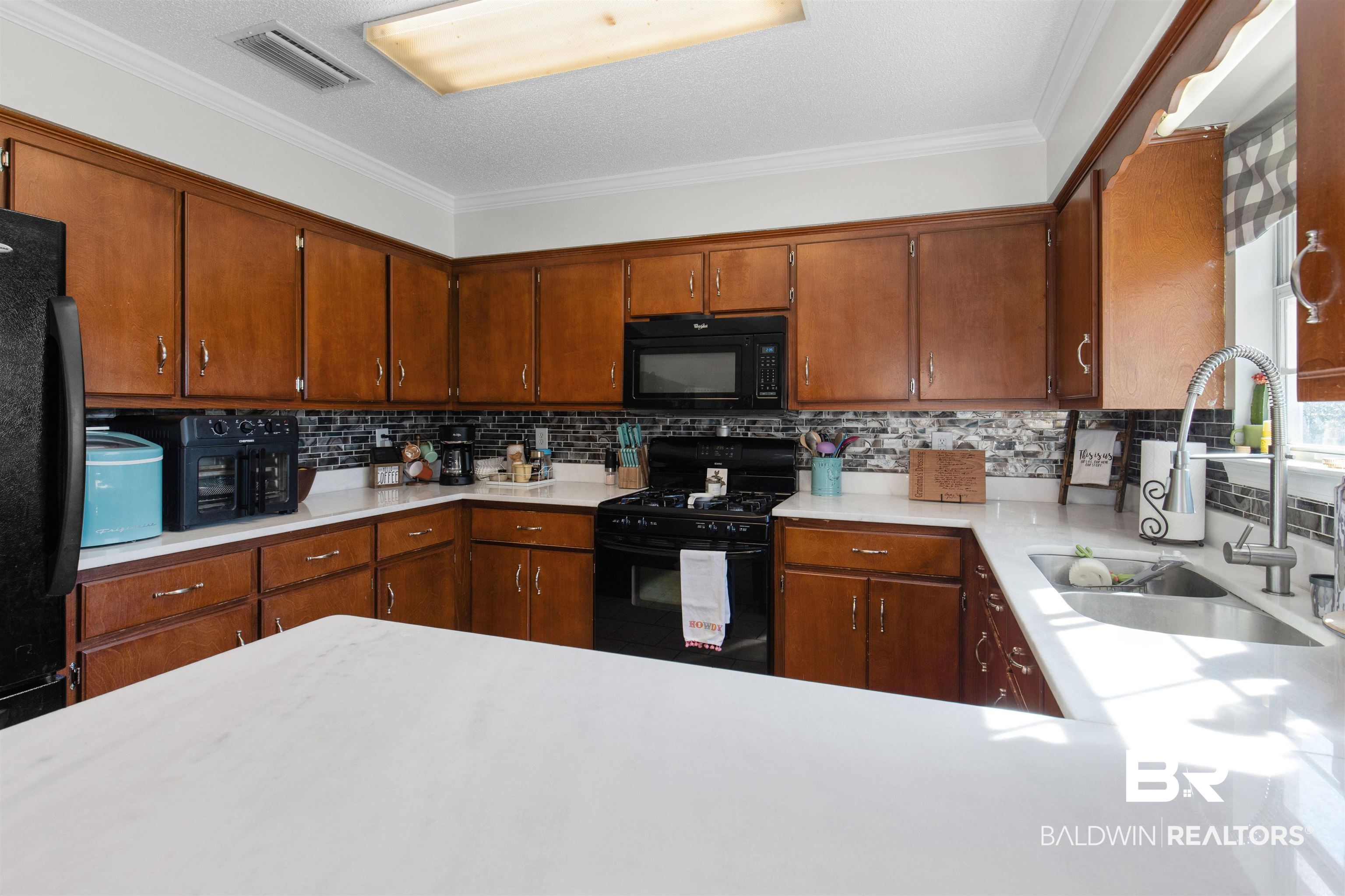 4950 Clealand Court Mobile, AL 36695 - Photo 7 of 20 Kitchen with tasteful backsplash, visible vents, light countertops, black appliances, and a sink