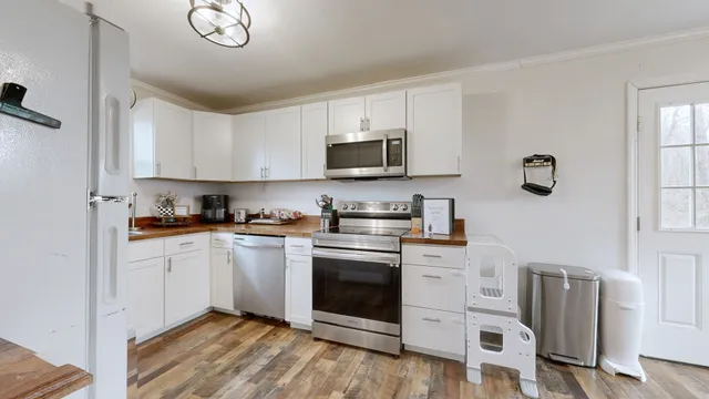 a kitchen with cabinets stainless steel appliances and wooden floor