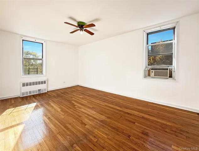 a view of empty room with wooden floor and fan