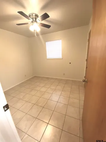 an empty room with windows and fan