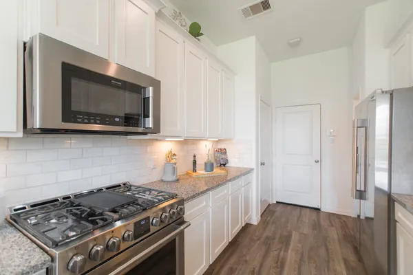 a large kitchen with stainless steel appliances granite countertop a lot of counter space and wooden floor