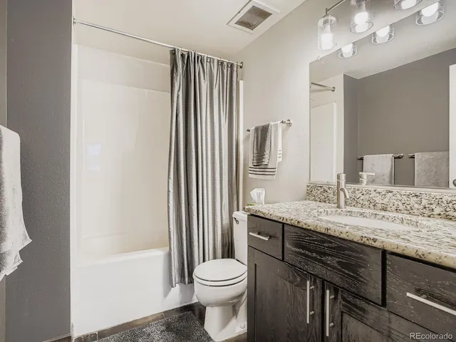 a bathroom with a granite countertop sink toilet and shower