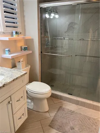 a bathroom with a granite countertop toilet a sink and a shower