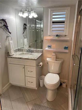 a bathroom with a granite countertop toilet sink and mirror