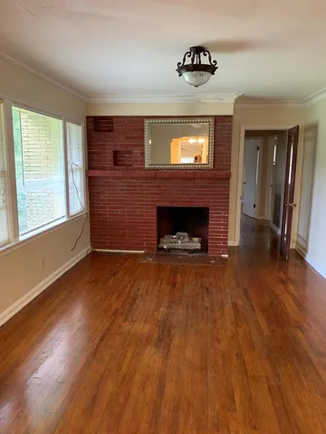 an empty room with wooden floor fireplace and windows