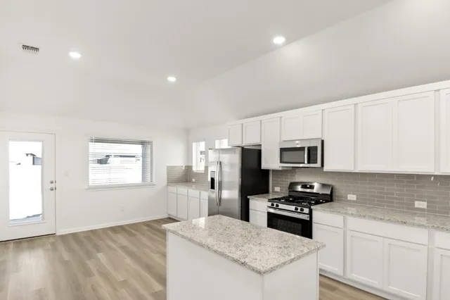a kitchen with granite countertop stainless steel appliances a refrigerator and a stove top oven