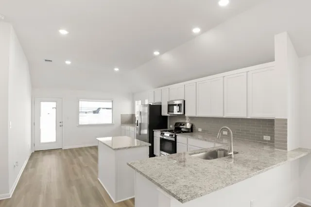 a kitchen with sink a microwave and cabinets