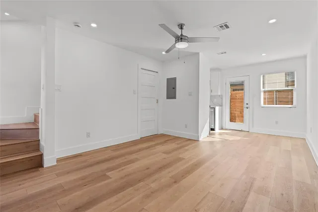 an empty room with wooden floor a ceiling fan and windows