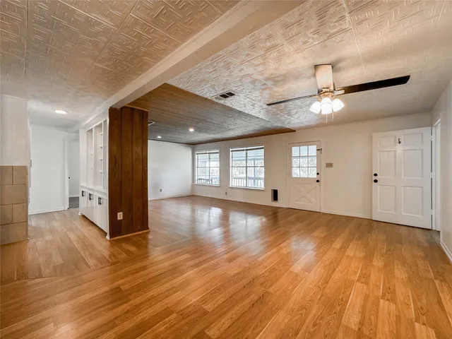 a view of an empty room with window and wooden floor