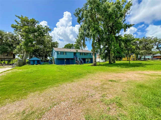 a view of a house with a big yard and large trees