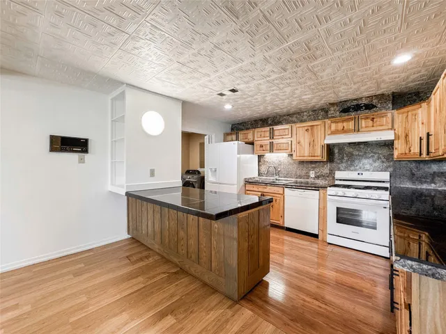 a kitchen with stainless steel appliances granite countertop a sink a stove and a wooden floors