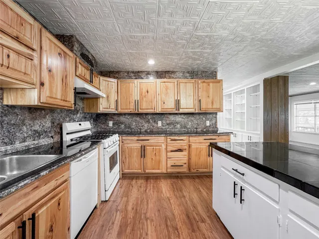 a kitchen with stainless steel appliances granite countertop wooden cabinets granite counter tops and a hard wood floors