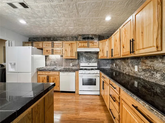 a kitchen with stainless steel appliances granite countertop a sink a stove and a refrigerator