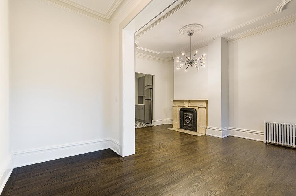 118 Mercer Street Jersey City, NJ 07302 - Photo 24 of 33 an empty room with wooden floor fireplace and staircase