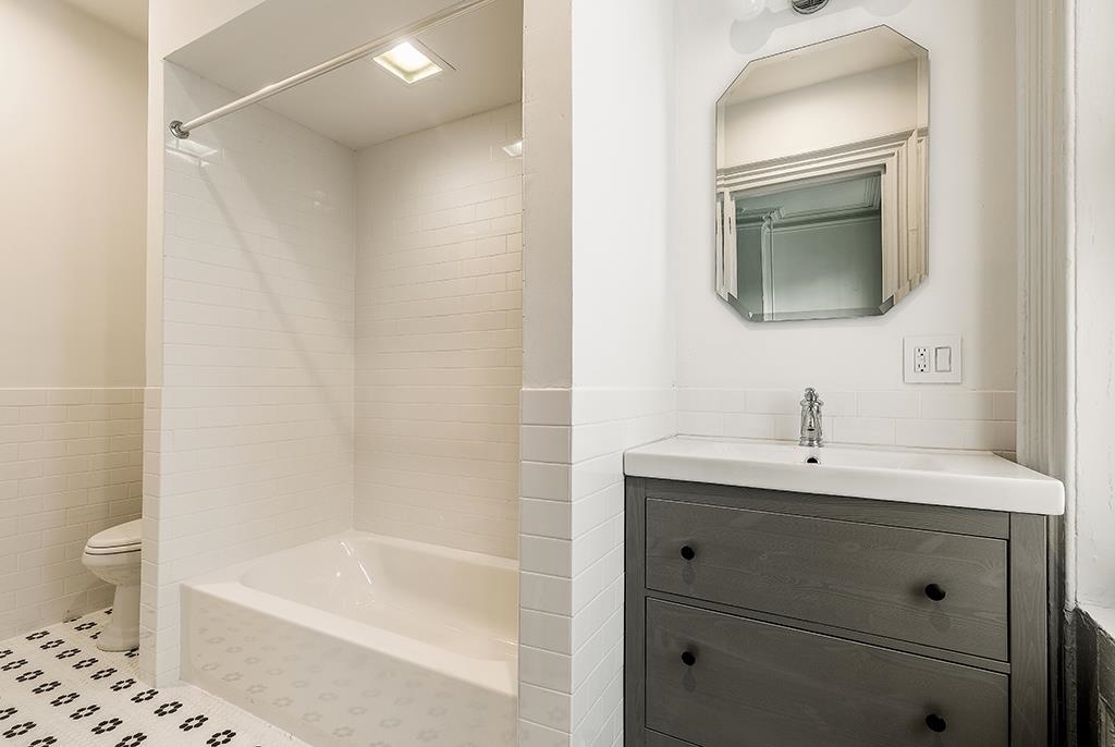118 Mercer Street Jersey City, NJ 07302 - Photo 30 of 33 a bathroom with a bathtub a sink a toilet and a mirror