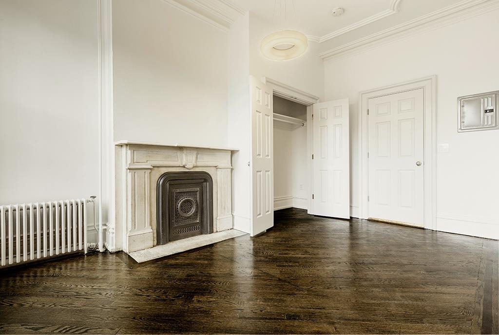 118 Mercer Street Jersey City, NJ 07302 - Photo 33 of 33 an empty room with wooden floor fireplace and windows