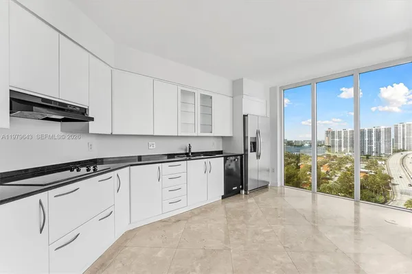 a open kitchen with granite countertop a sink and white cabinets next to a window