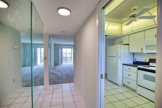 a view of a refrigerator in kitchen and an empty room in wooden floor