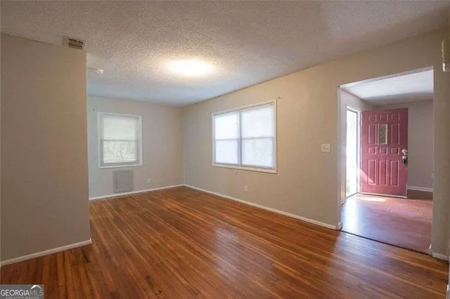 a view of an empty room with wooden floor and a window