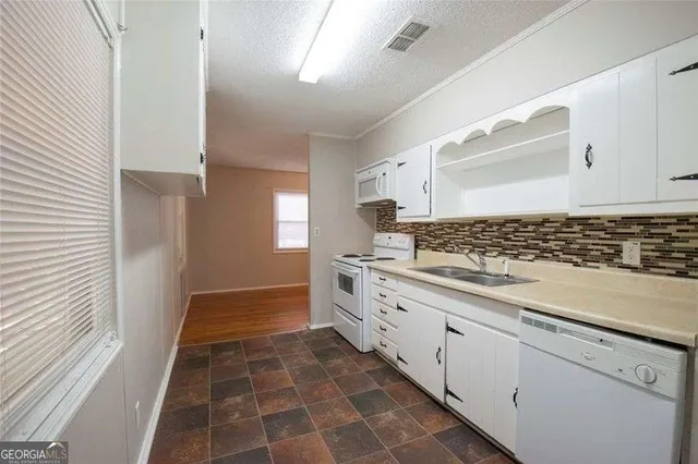 a kitchen with granite countertop white cabinets and white appliances