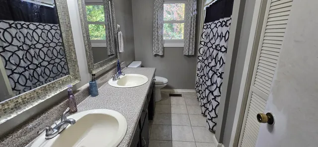 a bathroom with a granite countertop sink a toilet and shower curtain