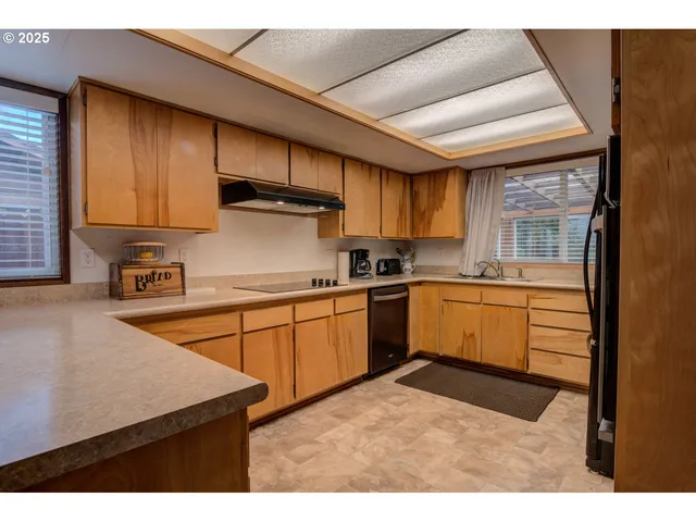 a kitchen with stainless steel appliances kitchen island granite countertop a refrigerator a stove and a sink with large cabinets