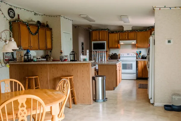 a kitchen with granite countertop a stove top oven a sink dishwasher and white cabinets with wooden floor