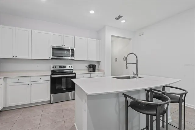 a kitchen with a sink a stove and white cabinets