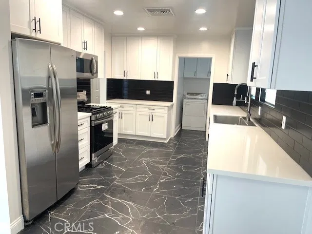 a large kitchen with stainless steel appliances kitchen island granite countertop a refrigerator and a stove top oven with wooden floor