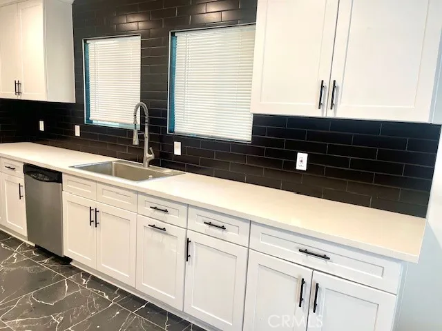 a kitchen with granite countertop white cabinets and black appliances