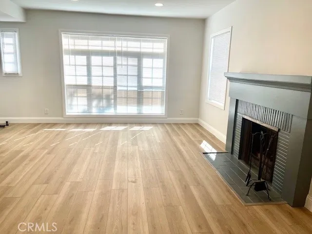 a view of an empty room with wooden floor and a fireplace