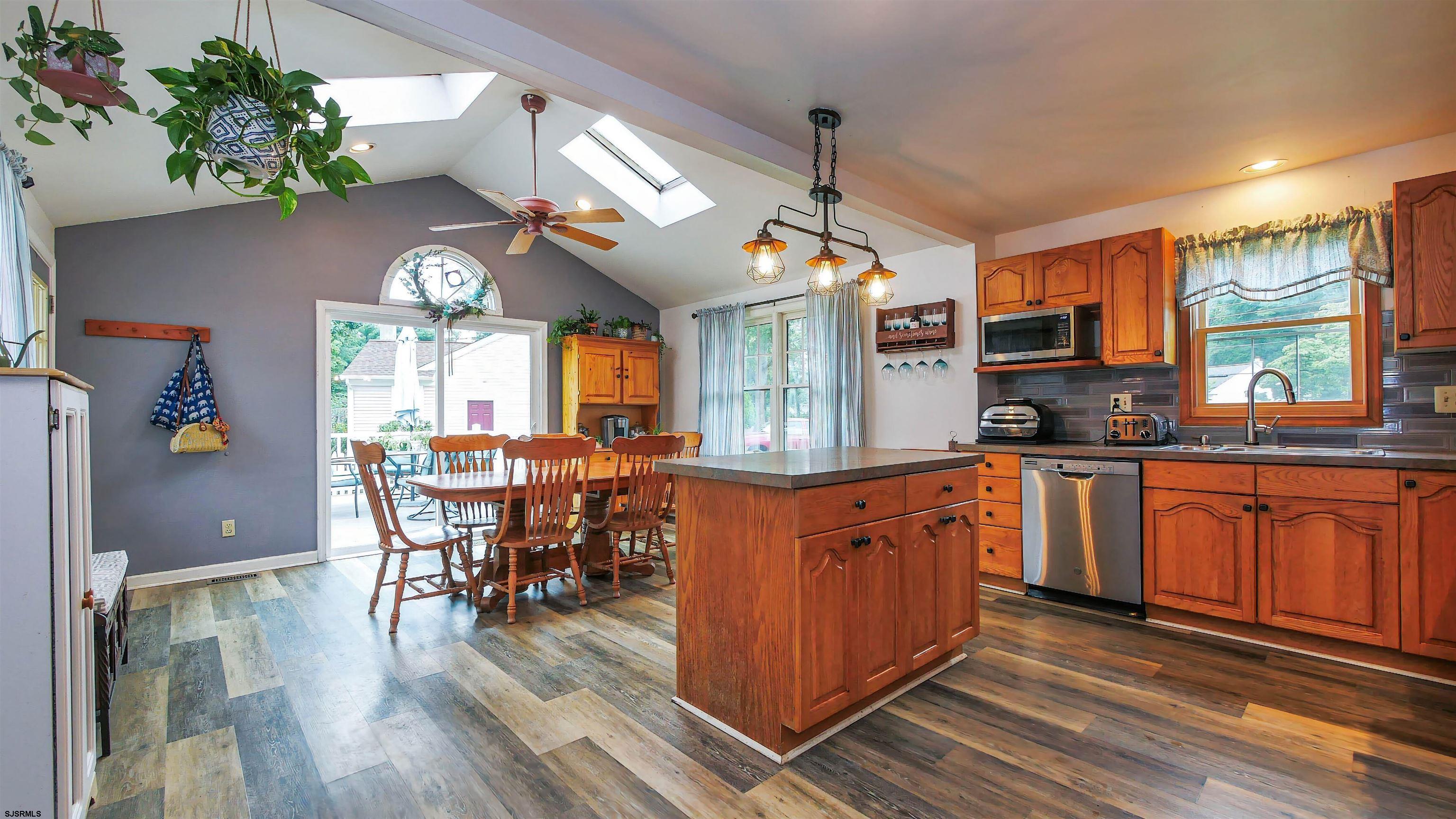2 Rose Lane Somers Point, NJ 08244 - Photo 7 of 43 a kitchen with stainless steel appliances granite countertop a stove top oven a refrigerator a dining table and chairs with wooden floor