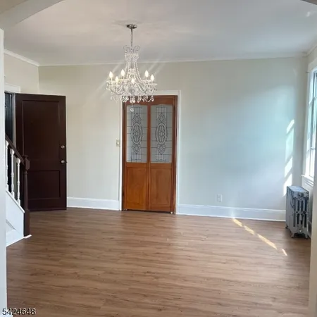 a view of a livingroom with wooden floor staircase and a kitchen space