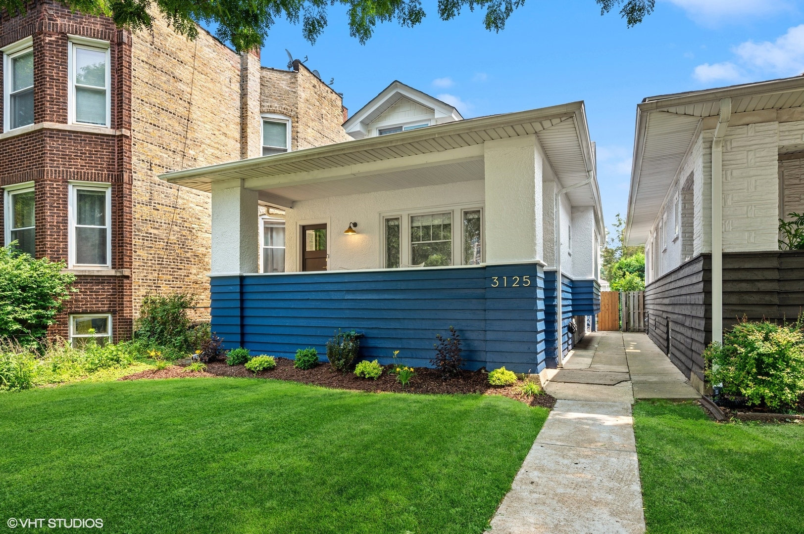 a view of a house with brick walls and a yard with plants