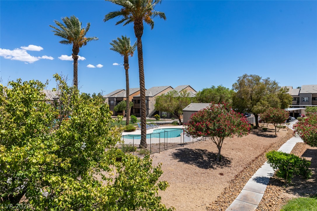 6650 West Warm Springs Road, Unit 2118 Las Vegas, NV 89118 - Photo 34 of 41 Palm trees shade a vibrant community pool area with well-maintained grounds and residential buildings in the background.