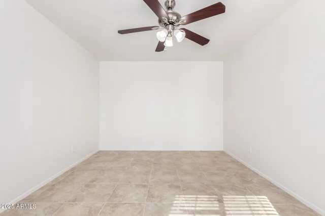 an empty room with chandelier fan and windows