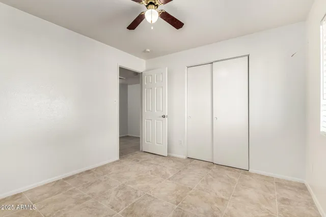 an empty room with a window and a fan