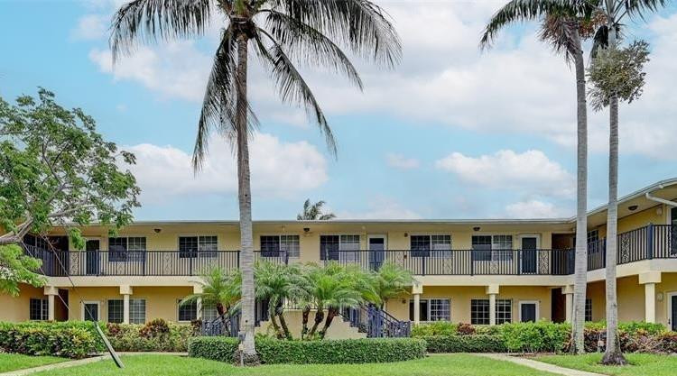 410 Southwest 15th Street, Unit 103 Pompano Beach, FL 33060 - Photo 2 of 16 a front view of a residential apartment building with yard and green space